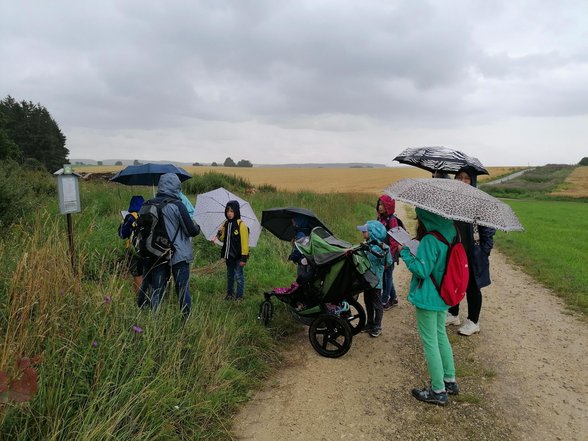 eine Gruppe läuft in der Landschaft mit Regenschirm